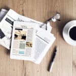 Newspaper with tablet on wooden table