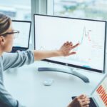 Business woman study financial market to calculate possible risks and profits.Female economist accounting money with statistics graphs pointing on screen of computer at desktop. Quotations on exchange